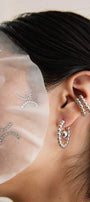 Close-up of an ear wearing silver hoop earrings and a pair of silver ear cuffs