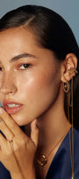 Woman wearing gold transforming jewelry including earrings, cuff, and necklace 