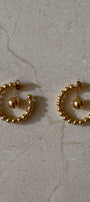 Pair of gold hoop earrings on a beige marble surface