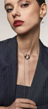 Woman wearing a necklace with a link-shaped pendant against a neutral background