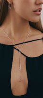 Woman wearing a delicate silver necklace and hoop earrings