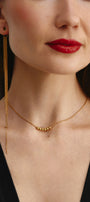 Close-up of a woman wearing a gold choker with dangling earring