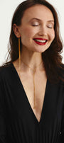 Woman wearing a gold transforming necklace with a long mono earring