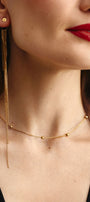 Close-up of a woman wearing gold mono earring and delicate choker with beads 