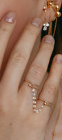 Hand wearing two gold rings with a cubic-zirconia connector
