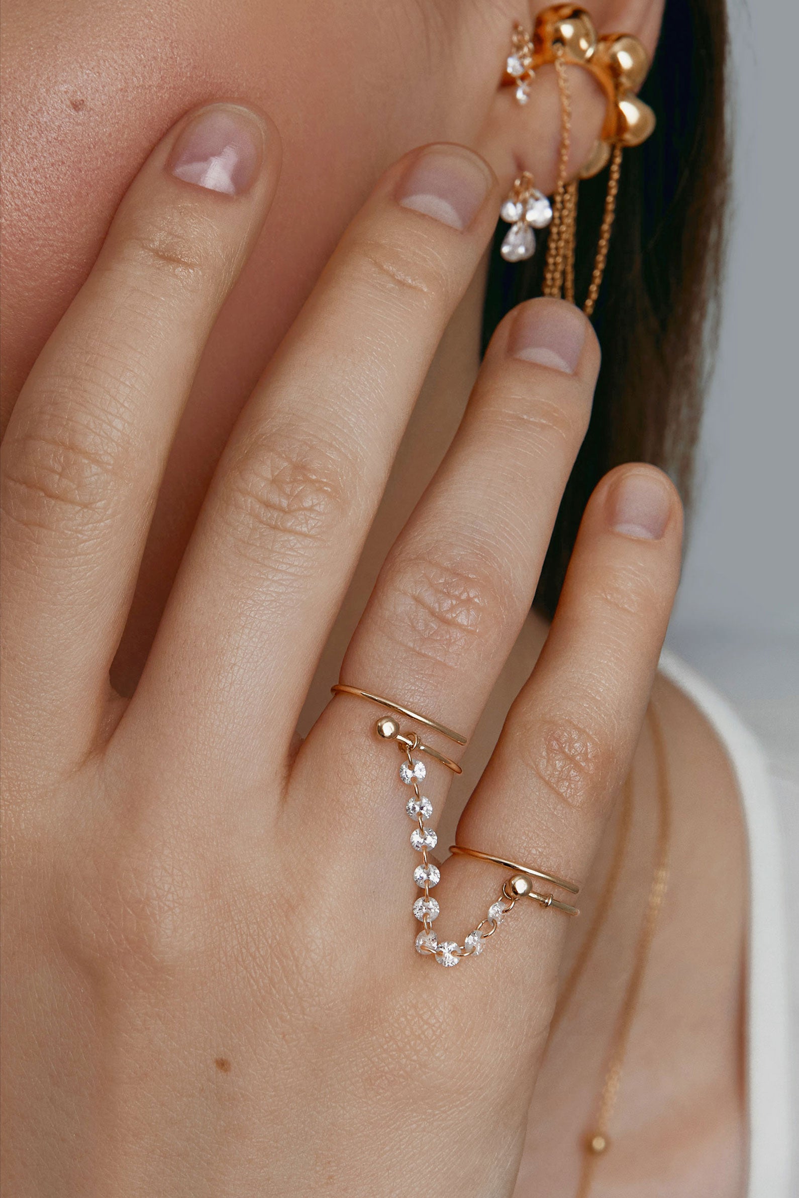 Hand wearing two gold rings with a cubic-zirconia connector