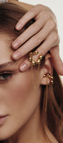 Close-up of a person wearing gold transforming cuff and a ring on a neutral background