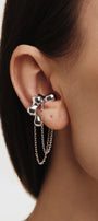 Silver flower-shaped ear cuff with chain detail worn by a person