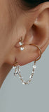 Close-up of an ear wearing gold cuff and tiny earrings with gems