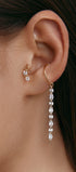 Close-up of an ear wearing gold ear cuff with long gems pendant 