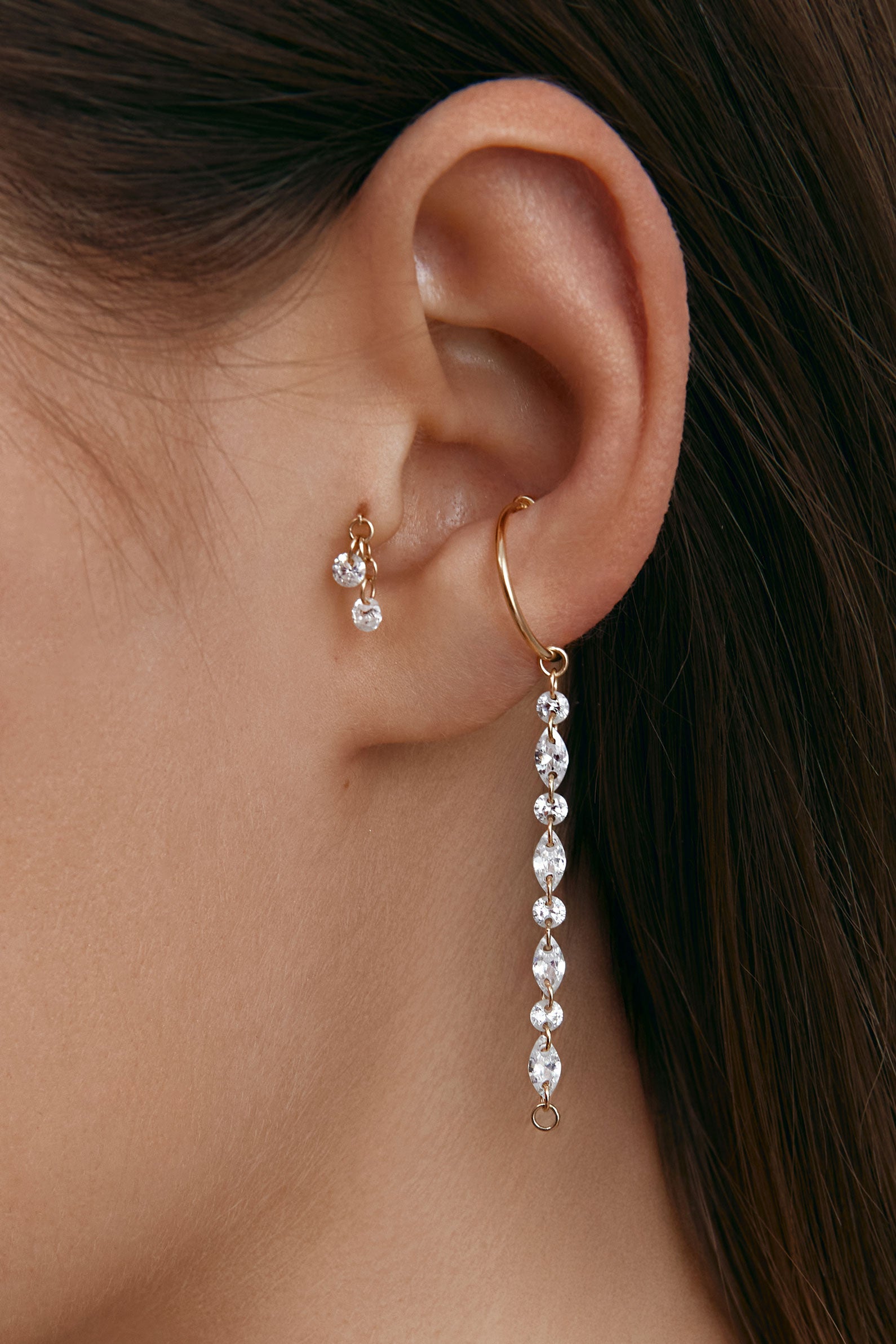 Close-up of an ear wearing gold ear cuff with long gems pendant 
