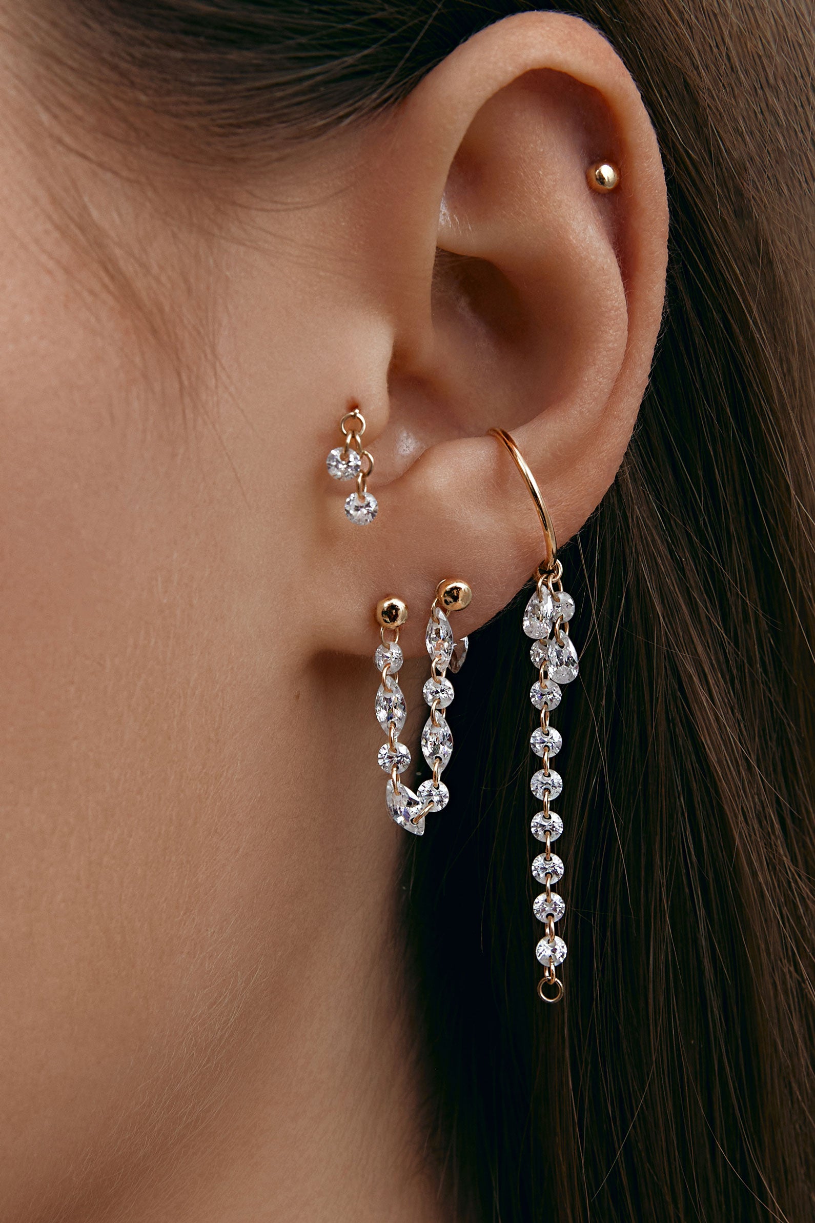 Close-up of an ear wearing gold modular jewelry with gems