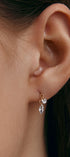 Close-up of an ear wearing a delicate earring with a marquise cut gem