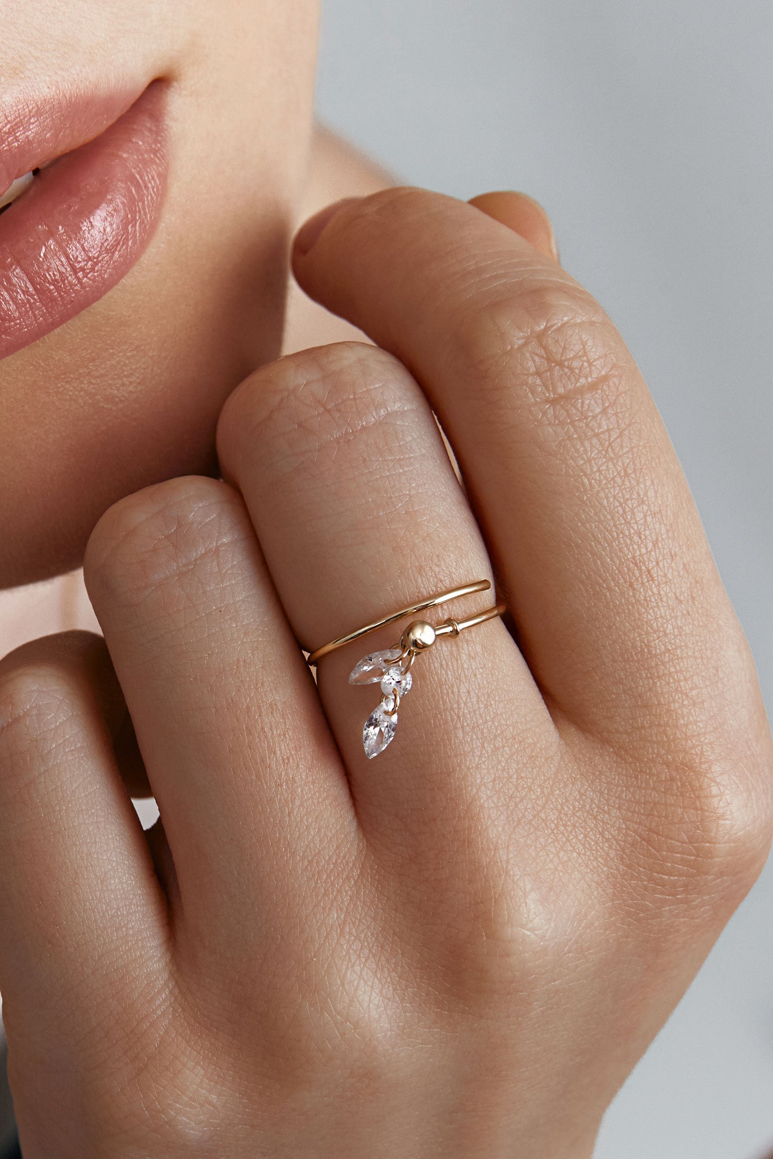 Close-up of a hand wearing a gold ring with a marquise cut gems