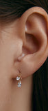 Ear wearing a gold earring with a pear-shaped gem 