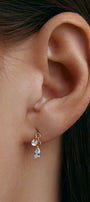 Ear wearing a gold earring with a pear-shaped gem 