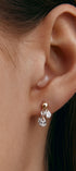 Close-up of an ear wearing a gold earring with pear-shaped gems