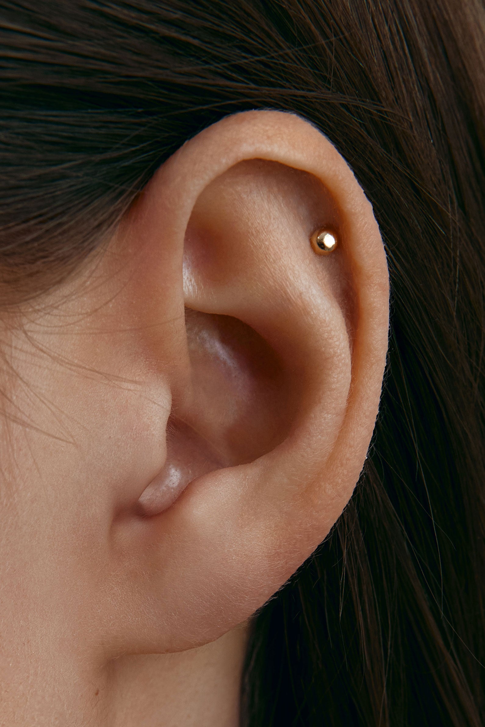 Close-up of an ear with a small gold stud earring