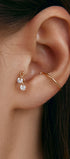 Close-up of an ear wearing gold tragus earring with round gems