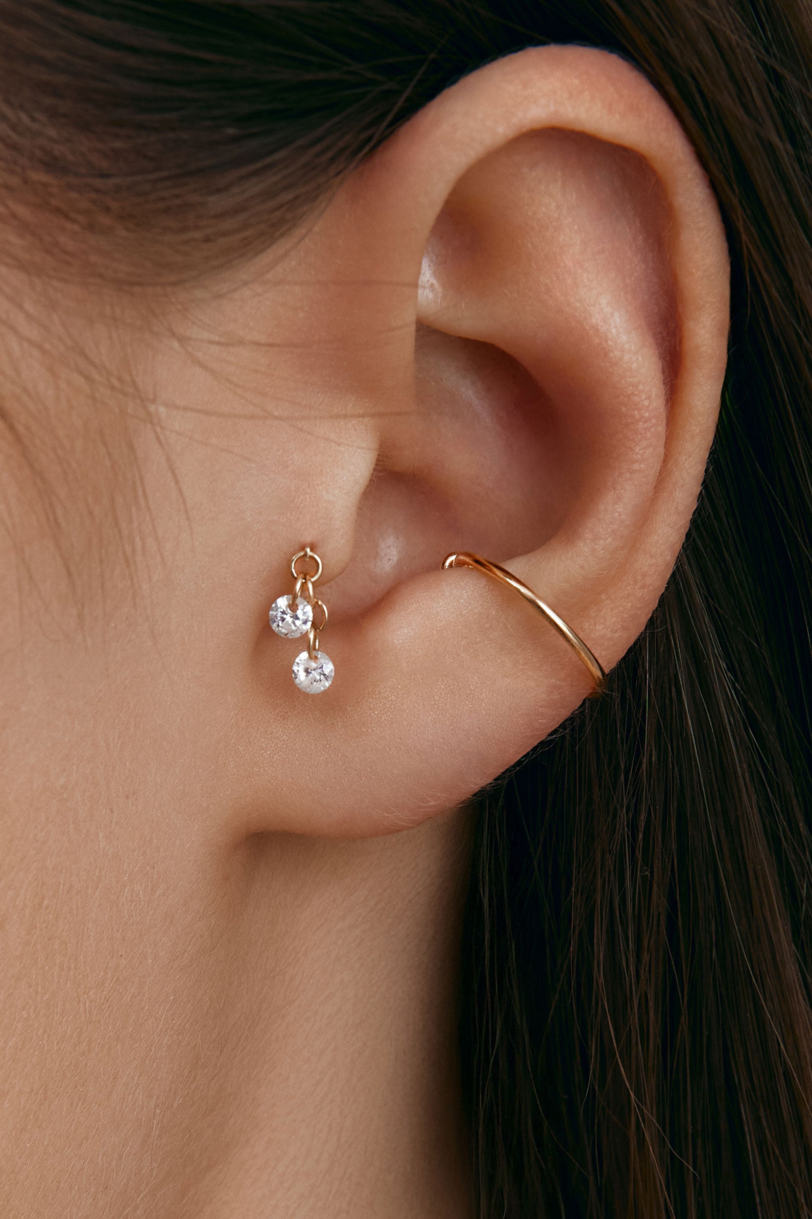 Close-up of an ear wearing gold tragus earring with round gems