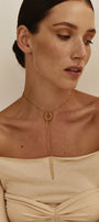 Woman wearing a gold transforming necklace against a plain background