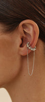 Close-up of an ear wearing a delicate silver ear cuff with a chain and small beads