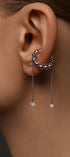 Close-up of an ear wearing a silver earring with dangling gems 