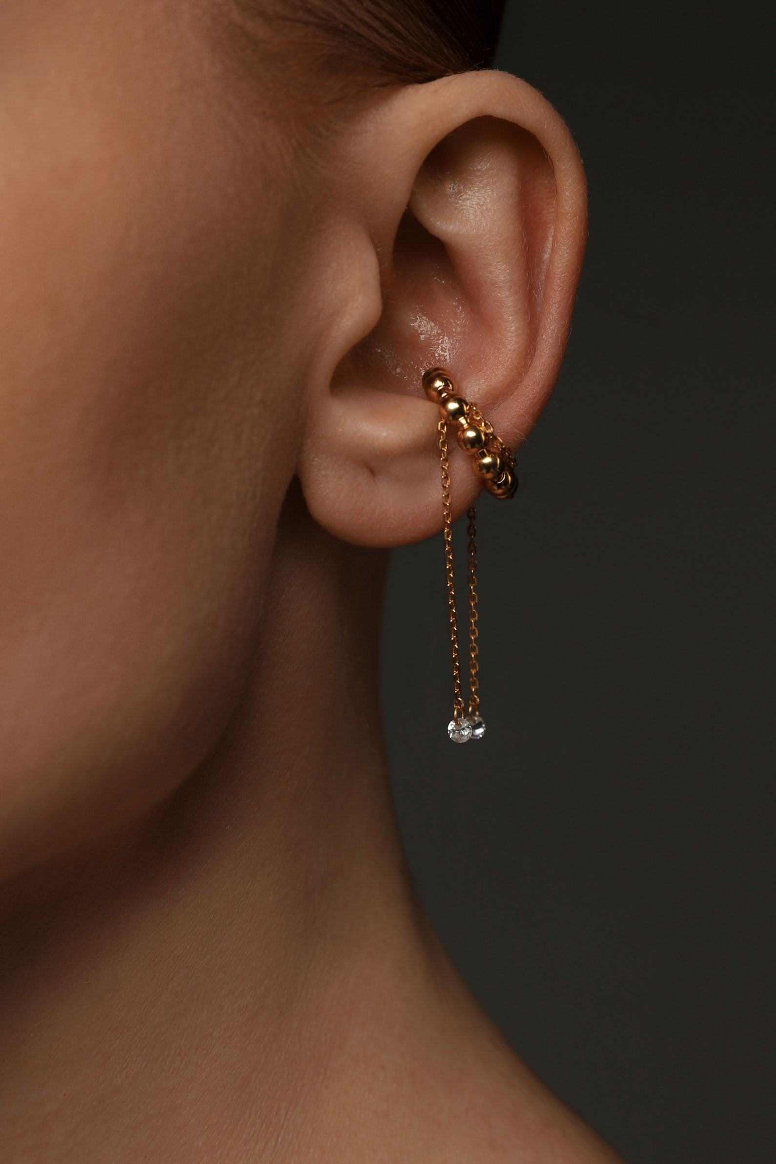 Gold ear cuff with chains and gems on the ear
