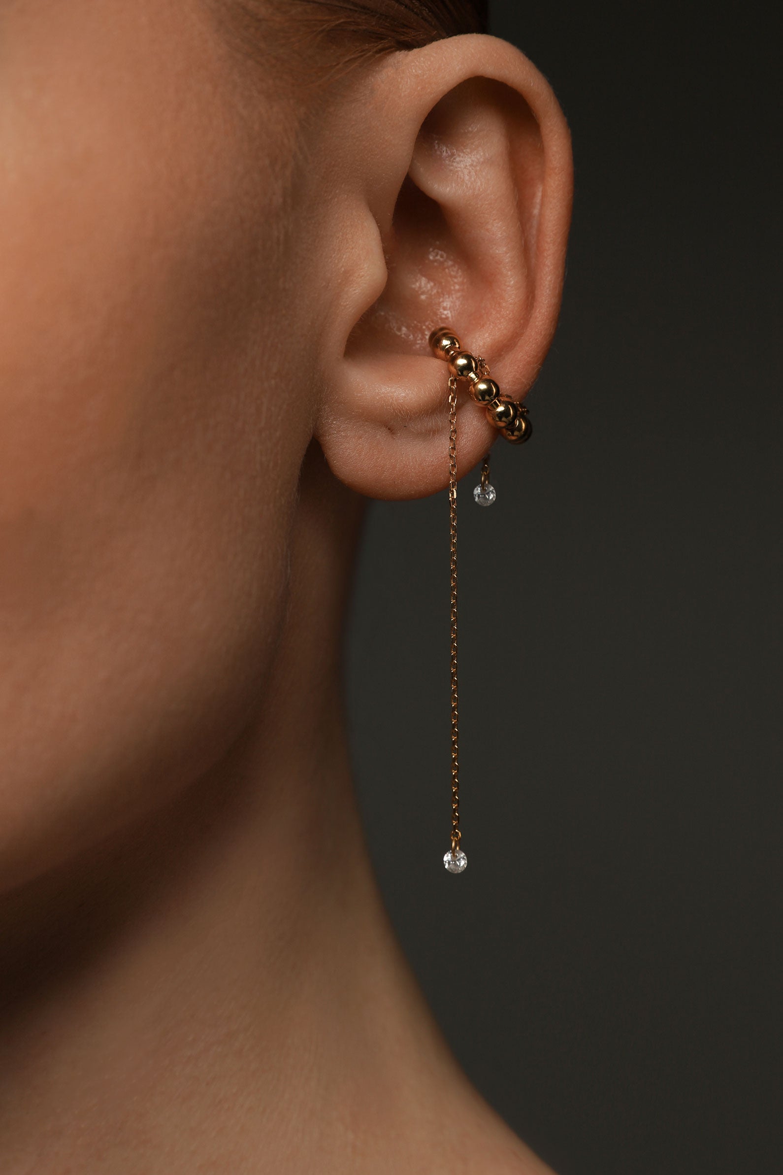 Close-up of an ear with a gold ear cuff with gems
